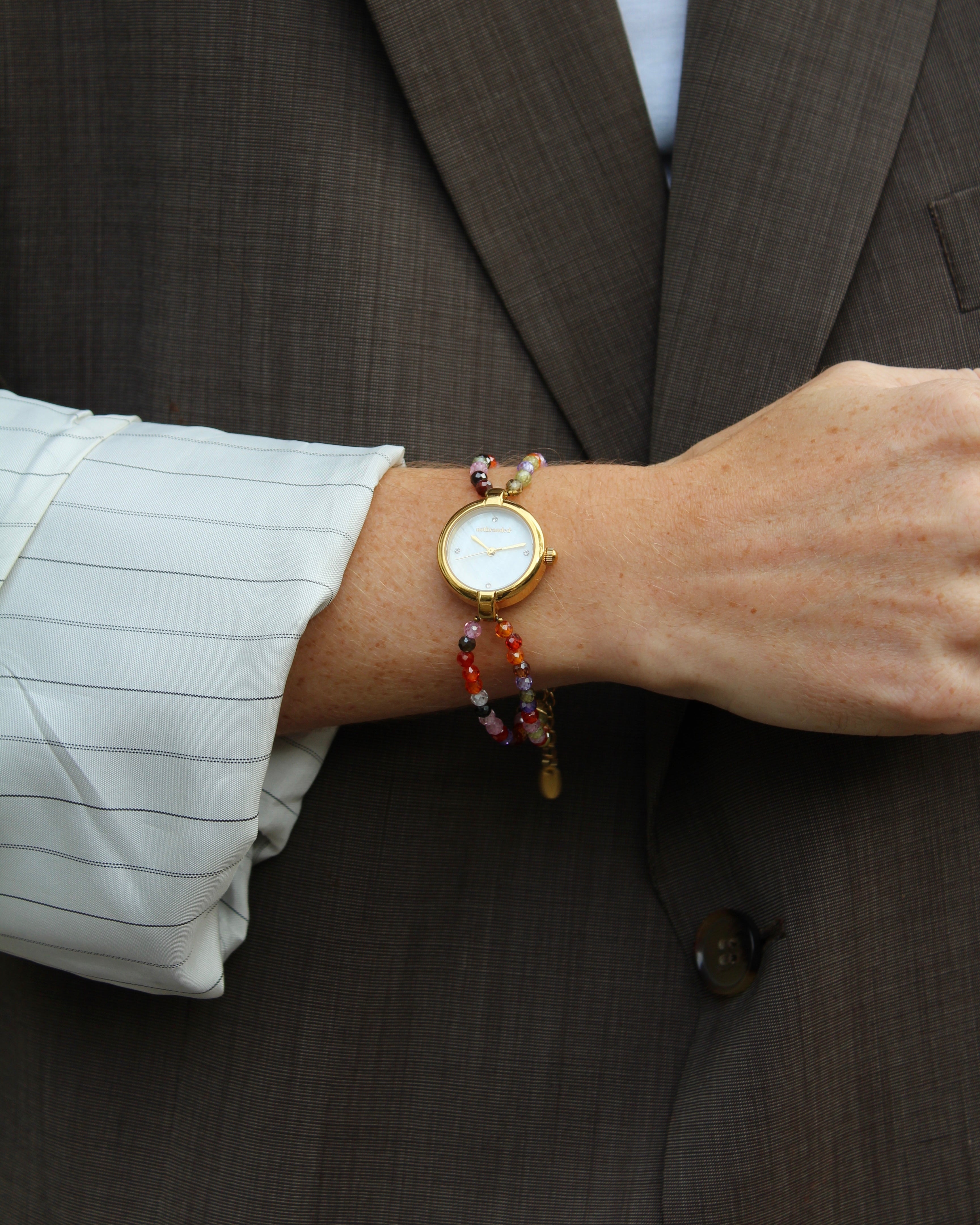horloge met kralen aan een arm met een blazer